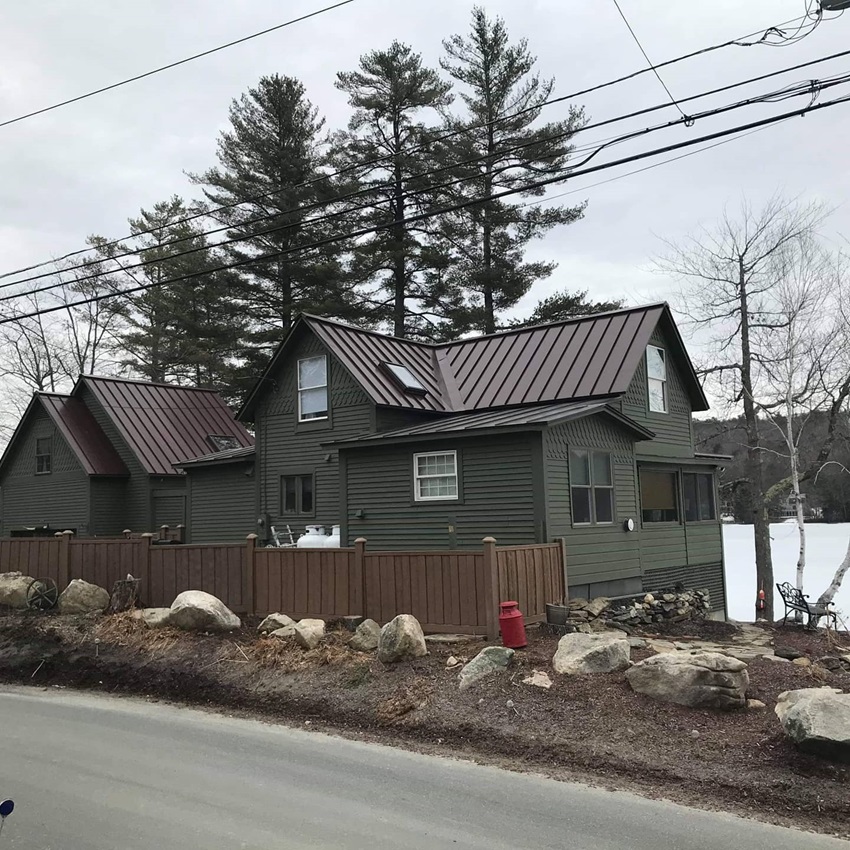 A House With A Metal Roof And A Wooden Fence